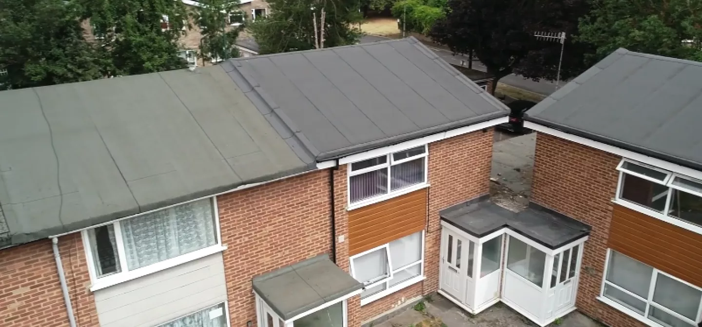 Aerial view of two connected brick houses with small porches.
